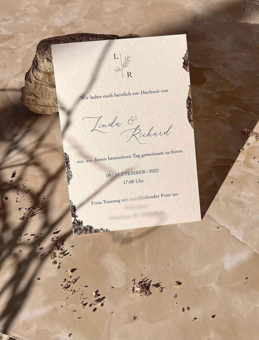 Elegante Hochzeitseinladung aus Büttenpapier mit Blattgold und Eukalyptus-Design auf Marmor
